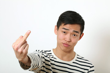 Displeased young Asian man giving the middle finger sign and loo
