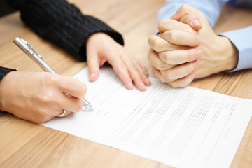 Man  with his hands clasped is waiting woman to sign the contrac