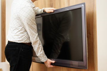 repairman gives television down from the wall in living room