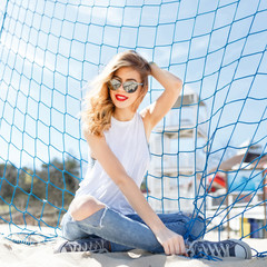 Trendy young girl posing  a background of blue on a beach.