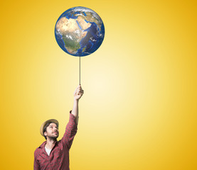 Close up of human hand holding Earth planet on rope. 