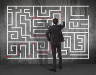 Businessman drawing labyrinth on wall