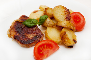 Grilled pork steak swith grilled potato and fresh tomato 