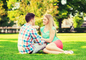 Fototapeta premium smiling couple sitting on grass in park