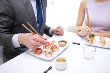 close up of couple eating sushi at restaurant