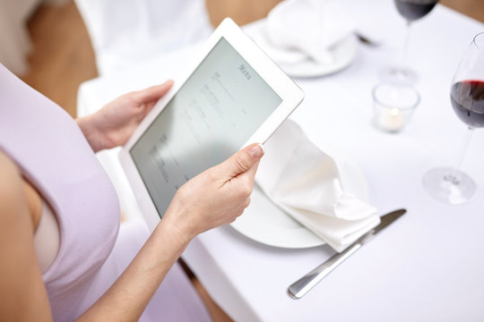 close up of woman with tablet pc at restaurant