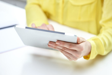 close up of female hands with tablet pc at table