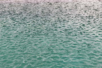 water surface with raindrops at rainy day