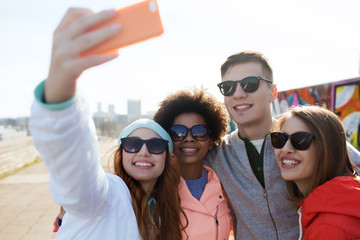 smiling friends taking selfie with smartphone