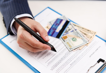 Closeup of businessman hand signing document in office