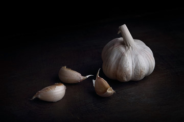 Garlic cloves on the black wooden table. Black background