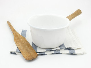 White boiling pan and wooden spatula on a fabric