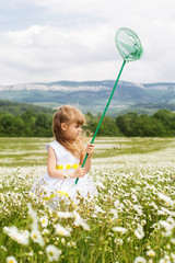 Cute child girl at field of camomiles with net