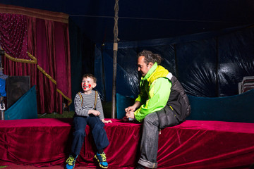 Boy Dressed as Clown Sitting on Stage with Man