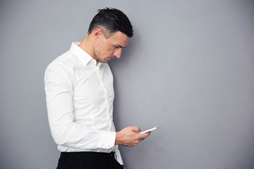 Businessman using smartphone over gray background