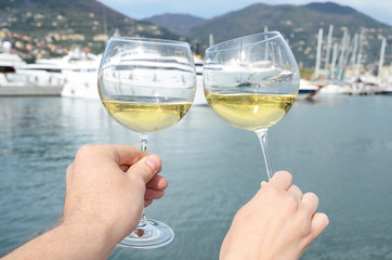 Obraz premium Pair of wineglasses in the hands against the yacht pier of La Sp