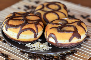 Three traditional donuts with chocolate on the brown plate