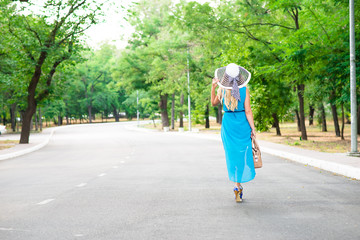 Beautiful young woman walking on the summer park