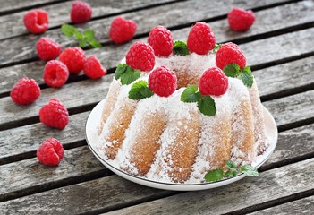 Vanilla bundt cake with  raspberries on a rustic dark background