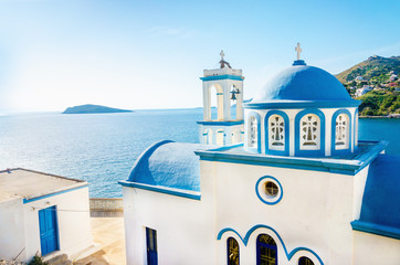 Typical Greek blue dome of white church with sea view in sunny d