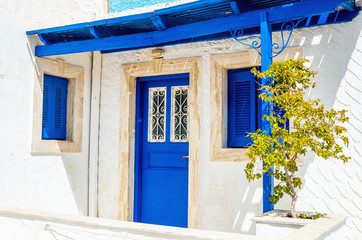 Fototapeta na wymiar Iconic view on wooden blue doors and windows with shade from roo