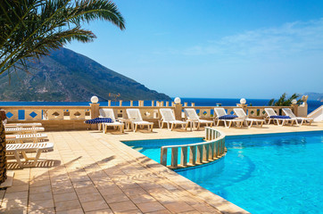 Fototapeta na wymiar Amazing view on swimming pool area and sunbeds under palm tree w