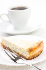Wedge of cheesecake with dessert fork and cup of coffee