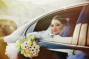 close-up portrait of pretty shy bride in a car window