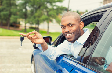 happy smiling young man sitting in his new car showing keys