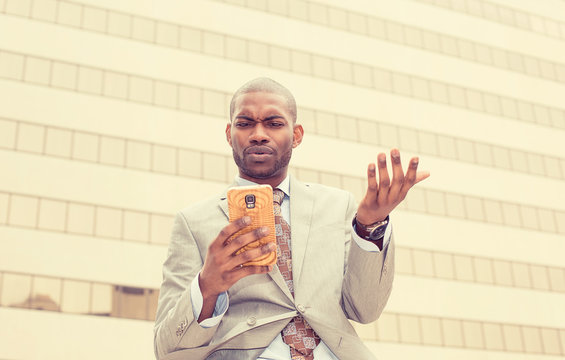 unhappy young man in suit talking texting on cellphone outdoors