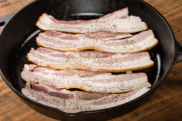 Frying pan with rows of raw bacon