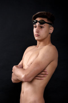 Portrait of a young man with swimming goggles on black backgroun