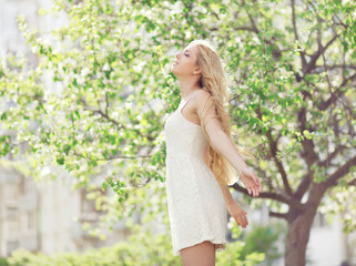 Fototapeta na wymiar Beautiful young woman enjoying smell in a flowering garden