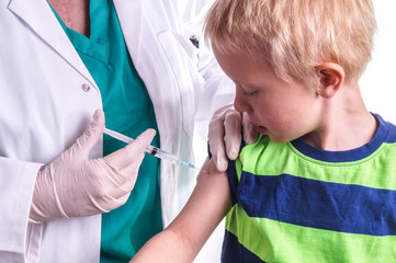 little boy is given an injection by the family doctor