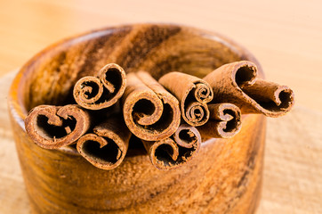 close up of cinnamon on wooden bowl isolated on white