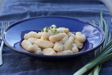 Gnocchi with oregano on a blue plate.