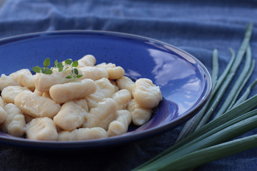 Gnocchi with oregano on a blue plate.