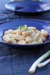 Gnocchi with oregano on a blue plate.