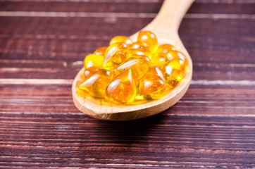 Fish oil on wooden spoon with wooden texture background