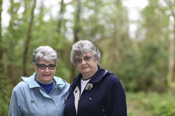 Elderly twin sisters walking in the woods