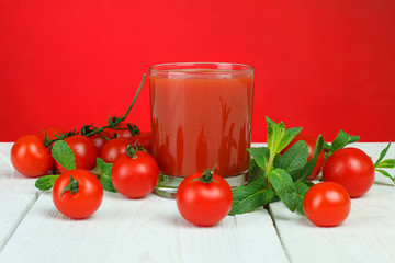 A glass of tomato juice and fresh tomatoes on a wooden table