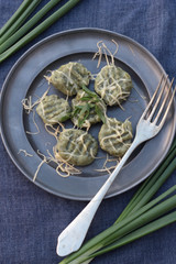 Gnocchi with spinach and grated cheese on a tin plate.