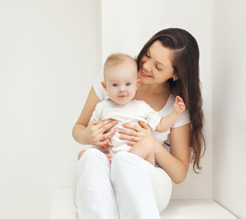 Happy young mother with baby at home in white room