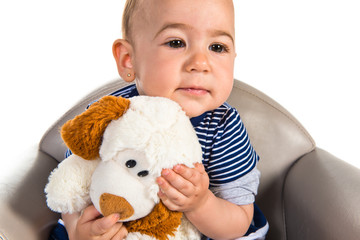 Baby with teddy sitting on small armchair