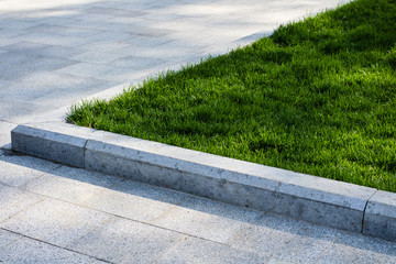 Trim the lawn in the park on the sidewalk - obrazy, fototapety, plakaty