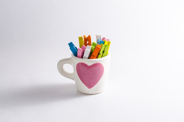 Group colorful pastel of wooden clothespins in coffee cup  isola