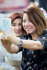 Happy asian woman with friend taking a selfie