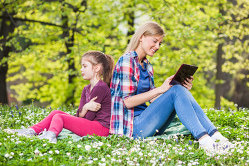 Fototapeta premium Older sister is using digital tablet and younger is angry