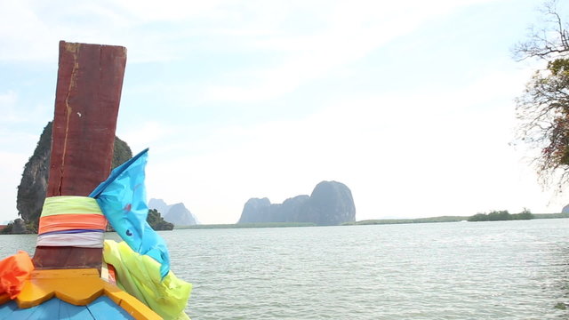 view of fabric flapping  on longtail boat drifting past cliff