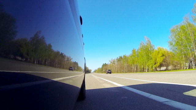 Driving a car. The camera is outside and aimed back.